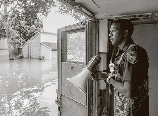  ?? Jon Shapley / Houston Chronicle ?? Harris County Sheriff’s Deputy Rick Johnson pauses to listen for voices as officials search for people in a neighborho­od inundated by water from the Addicks Reservoir.