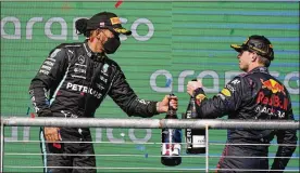  ?? DARRON CUMMINGS / ASSOCIATED PRESS ?? Red Bull driver Max Verstappen, of the Netherland­s, and Mercedes driver Lewis Hamilton, of Britain, his main rival, bump bottles following the Formula One U.S. Grand Prix auto race at the Circuit of the Americas Oct. 24 in Austin, Texas. Verstappen won the race and Hamilton finished second.