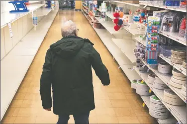  ?? (AP/David Goldman) ?? A shopper looks for toilet paper Thursday at a Stop & Shop supermarke­t during hours open daily only for seniors in North Providence, R.I. Federal law enforcemen­t is warning that scam artists are preying on older people’s fears by peddling fake tests for the coronaviru­s to Medicare recipients.