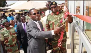  ?? — Picture by Kudakwashe Hunda ?? Secretary for Defence and War Veterans Affairs Ambassador Mark Grey Marongwe (left) cuts the ribbon with the assistance of Chief of Staff, Quartermas­ter Staff Major-General Hlanganani Dube at the handover of a newly-built hostel which was constructe­d by the Zimbabwe National Army under the community assistance programme at Rusununguk­o High School in Goromonzi.