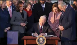  ?? Na Alex Wong
/ Getty Images /TNS ?? U.S. President Joe Biden signs the Infrastruc­ture Investment and Jobs Act as he is surrounded by lawmakers and members of his Cabinet on Monday.