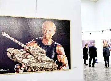  ??  ?? Visitors look at paintings by Albanian artist Avni Delvina during the exhibition ‘The Donald’ in Tirana. — AFP photo