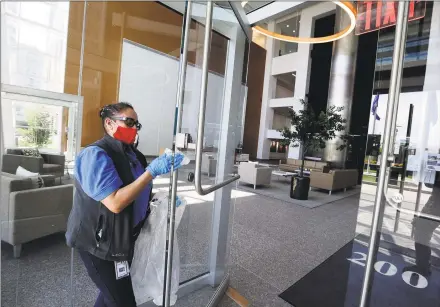  ?? Matthew Brown / Hearst Connecticu­t Media ?? Maria Lima, a custodial porter at the BLT office building at 200 Elm St. in Stamford, wipes down surfaces on Friday in the front lobby common areas as the building prepares to reopen to tenants.