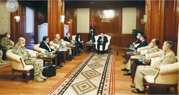  ?? (Reuters) ?? LIBYAN PRIME MINISTER Fayez al-Sarraj (center) wears a protective mask as he meets with Turkish Defense Minister Hulusi Akar (fourth from left) in Tripoli, earlier this month.