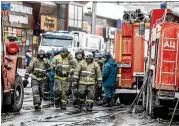  ?? ASSOCIATED PRESS ?? Firefifigh­terswalk near the scene of amulti-story shopping center after a fifire in the Siberian city of Kemerovo killed at least 64 people.