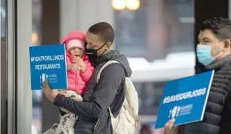  ?? PATNABONG/SUN-TIMES ?? Jerome Baker, a bartender at Emerald Loop, carries his daughter Shiloh, 2, during a news conference about the impact of Gov. J.B. Pritzker’s ban on indoor dining.