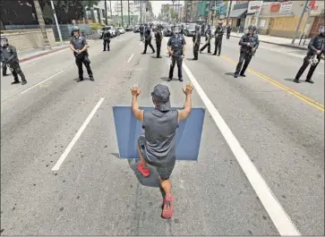  ?? Al Seib Los Angeles Times ?? PROTESTER Diego Martinez kneels in front of LAPD officers during demonstrat­ions June 2 in Hollywood against the killing of George Floyd. The department has been criticized for how it dealt the with protests.