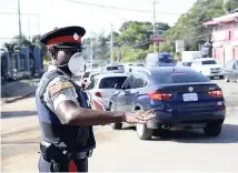  ??  ?? A police officer directs traffic at the intersecti­on of Constant Spring and Mannings Hill roads on Monday morning.