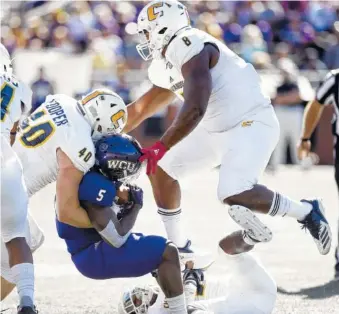  ?? STAFF PHOTO BY ROBIN RUDD ?? UTC’s Marshall Copper (40), Rashun Freeman, on ground, and Isaiah Mack tackle Western Carolina’s Connell Young during their SoCon matchup Oct. 13 in Cullowhee, N.C. Mack and fellow defensive linemen Khayyan Edwards and Derek Mahaffey have a weekly competitio­n to see who can get the most sacks in a game.