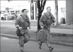  ?? AP/Houston Chronicle/MARK MULLIGAN ?? Law enforcemen­t officers run Monday toward the scene of a shooting in Houston that left several people injured.