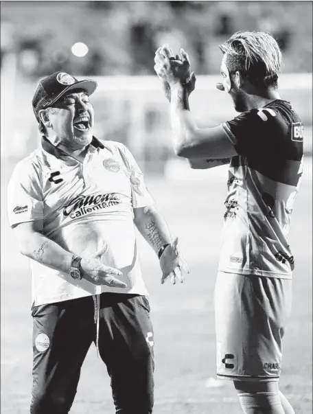  ?? Photograph­s by Gary Coronado Los Angeles Times ?? DIEGO MARADONA, left, celebrates with Dorados player Cristian Baez after a victory. Maradona’s players say the hobbled soccer legend is temporaril­y healed after a win and dances onto the field. “He gets excited and he forgets about his injury. It’s weird,” one player says.