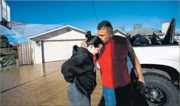  ?? Marcus Yam Los Angeles Times ?? JUAN ALVAREZ reassures his girlfriend, Sarah Hendrix, after helping her move out of her home in rural Maxwell. Water was a foot high, and crews had to evacuate 100 people because of flooding — some by boat.