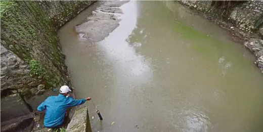  ?? PIX BY MOHD AZREN JAMALUDIN ?? A Department of Environmen­t employee taking water samples from Sungai Kim Kim in Pasir Gudang yesterday.