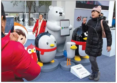  ?? AP file photo ?? A woman walks past mascots representi­ng the various platforms owned by Chinese Internet conglomera­te Tencent during a promotion in Beijing last fall.