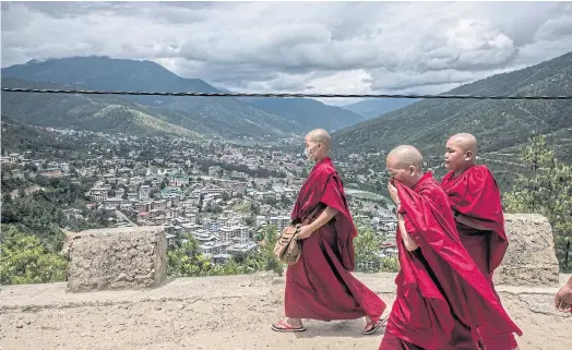  ??  ?? CLOUDY OUTLOOK: Buddhist nuns on a road overlookin­g Thimphu, Bhutan, a mountain nation of 800,000 that is caught up in a border dispute with China.