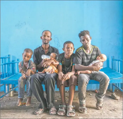  ?? (AP/Nariman El-Mofty) ?? Tigrayan refugee Abraha Kinfe Gebremaria­m, 40, (second left) sits for a photograph with his sons, Micheale, 5, (left); Daniel, 11, (center); his 19-year-old brother-in-law, Goytom Tsegay, (second right) and his 4-month-old twin daughters Aden, (right) and Turfu Gebremaria­m (on his lap( in the family’s shelter in Hamdayet, Sudan. A fellow refugee, Mulu Gebrenchea­l, a mother of five, has become an informal adviser, offering guidance on the babies’ care. Abraha and his sons are quick learners, she said. But she mourns for the twins and the death of their mother. “Even the hug of a mother is very sweet,” she said. “They’ve never had this. They never will.”