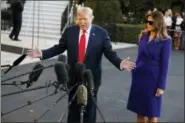  ?? EVAN VUCCI — THE ASSOCIATED PRESS ?? First lady Melania Trump looks on as President Donald Trump speaks with reporters before departing the White House for a trip to Asia, Friday in Washington.