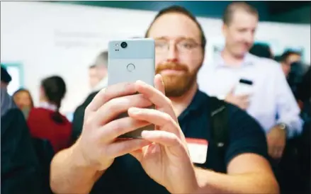  ?? ELIJAH NOUVELAGE/AFP ?? A member of the media holds up the ‘barely blue’ colour model of the Pixel 2 smartphone at a product launch event on Wednesday at the SFJAZZ Center in San Francisco, California.