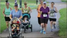  ??  ?? A group of women, including some pushing strollers, run along the Schuylkill River Trail in Pottstown as part of a 5K race held at Riverfront Park.