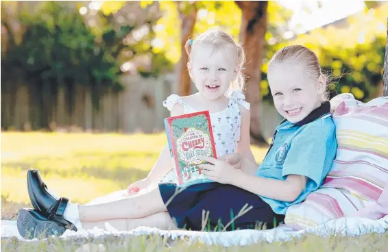  ?? Picture: MIKE BATTERHAM ?? Charli and Sienna Mackinnon read The Children of Cherry Tree Farm, which is available for just $3 with the Gold Coast Bulletin tomorrow.