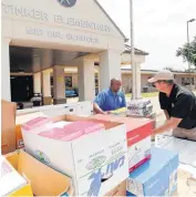  ??  ?? Delvon Patterson, left, and Shane Barnard, with Midwest City Neighborho­od Services, deliver school supplies to Tinker Elementary School.