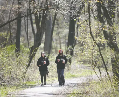  ?? DAN JANISSE ?? Autumn Zahara and Justyn Hilton peer up from their phones to appreciate budding trees while on a walk through Ojibway Park on Tuesday.