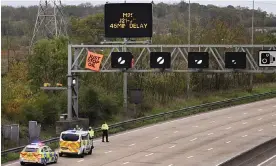  ?? Photograph: Leon Neal/Getty Images ?? Police officers attempt to stop an activist putting up a banner atop an electronic traffic sign along the M25 on 10 November.
