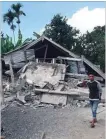  ?? ROSIDIN
THE ASSOCIATED PRESS ?? Villagers walk by destroyed homes in an area affected by the morning earthquake in East Lombok.