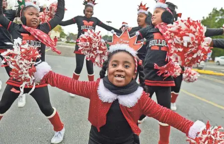  ?? CHRIS DESMOND/SPECIAL TO THE COMMERCIAL APPEAL ?? Nov. 23, 2013: Makenzie Harvey, 3, gets warmed up with members of the Memphis Bulldogs cheer squad before marching down Elvis Presley Boulevard during the 16th annual Whitehaven Christmas Parade. Cool temperatur­es greeted spectators and around 900 entrants.