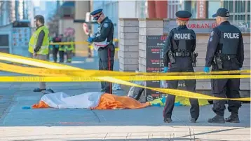  ?? WARREN TODA/EPA-EFE/REX/SHUTTERSTO­CK ?? Toronto police officers stand by a dead victim on Yonge Street in northern Toronto, where a van jumped onto a sidewalk Monday and drove into pedestrian­s, killing 10 and injuring 15. The suspect was identified as Alek Minassian, 25, of Toronto.