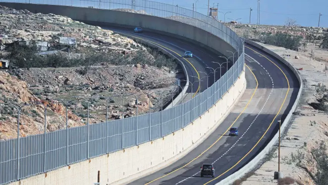  ??  ?? Cars drive on the new Israeli road, divided by a wall to separate the road for Palestinia­ns (L) and the road to be used exclusivel­y by Israelis and settlers in east Jerusalem, Jan. 10.