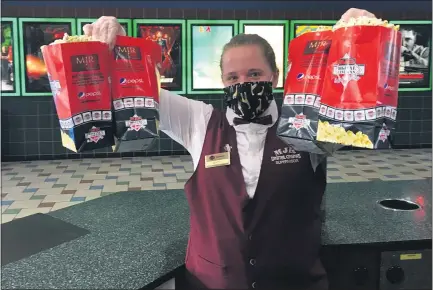  ?? PHOTOS BY GINA JOSEPH — THEMACOMB DAILY ?? MJR Chesterfie­ld Crossing Digital Cinema 16team player Macy Korn holds up a fewbags of the popcorn she has ready for guests. After seven months of being closed during the coronaviru­s pandemic, MJR is among the theater reopening on Friday.