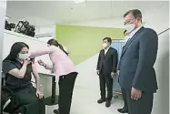  ??  ?? 韩国总统文在寅（右一）观看一名医生接种阿斯­利康疫苗。（美联社照片）