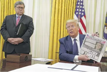  ?? EVAN VUCCI/AP ?? Attorney General William Barr looks on as President Donald Trump holds up a copy of the New York Post in the Oval Office before signing an executive order Thursday aimed at curbing protection­s for social media giants.