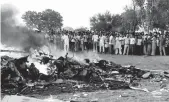  ?? — PTI ?? People watch the burning IAF helicopter which crashed in Sitapur on Friday.