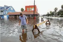  ?? Steve Gonzales / Staff photograph­er ?? Travis Eifert trudges away from Napalera Galveston restaurant as high water closed down some streets Friday in Galveston.