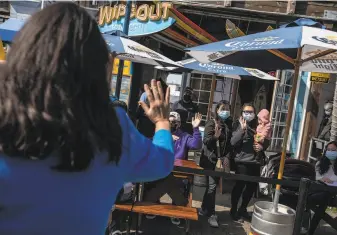  ?? Stephen Lam / The Chronicle ?? Mayor London Breed waves to visitors at the Wipeout Bar & Grill at Pier 39 after announcing that San Francisco would move to the less restrictiv­e red tier in the state system.