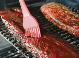  ?? Photos by Kin Man Hui / Staff photograph­er ?? Barbecue sauce is applied to baby back ribs during the final stage of smoking.