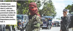  ??  ?? A MORO Islamic Liberation Front (MILF) rebel (L) with face covered, along with a government soldier (R) manning a checkpoint in Datu Salibo town, Maguindana­o province, Sept. 5.