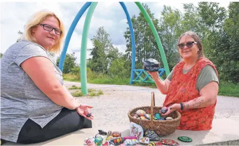  ?? RP-FOTO: LAASER ?? Elke Krölls (r.) und Sabrina Schiffer bemalten Steine und verteilen sie am Wegesrand, wie hier am Nordtor an der Rur bei Millich.