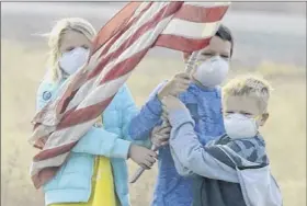  ??  ?? Children stand on the side of the road holding an American flag Saturday as the motorcade of President Donald Trump drives through Chico, Calif. The death toll stood at 71 Saturday.