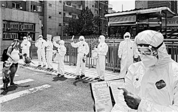  ?? KEVIN FRAYER/GETTY ?? Workers in Beijing hold up signs as travelers make their way Monday to a residentia­l compound as part of quarantine measures after arriving in China.