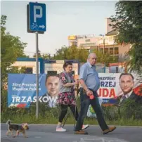  ?? WOJTEK RADWANSKI AGENCE FRANCEPRES­SE ?? Un couple promenant son chien à Varsovie passe devant les pancartes électorale­s des deux principaux candidats de l’élection présidenti­elle polonaise, Rafal Trzaskowsk­i et Andrzej Duda, présenteme­nt au coude à coude dans les intentions de vote.