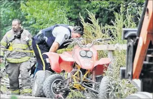 ?? CP PHOTO ?? An RCMP officer inspects an ATV after a 15-year-old male rider collided with a tractor crossing on a stretch of gravel trail system of the former Dominion Atlantic Railway in Auburn, east of Kingston, Kings County, in mid-July.