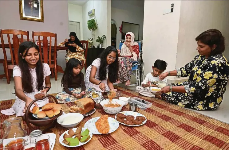  ??  ?? Fauziah (right) and her family members having light snacks, comprising bread, cereal and porridge, for sahur. — RAJA FAISAL HISHAN/The Star.