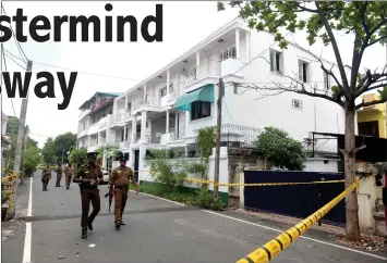  ??  ?? cile photo shows pri iankan security forces walking past a house in Colombo where a raid occurred after a suicide blast. — Acm photo