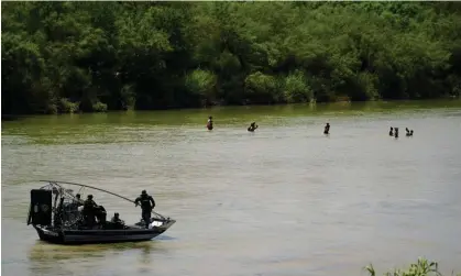  ?? Photograph: Eric Gay/AP ?? Texas state troopers watch as migrants cross the Rio Grande near Eagle Pass, Texas, on 10 July 2023.