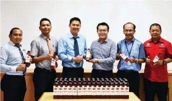  ??  ?? Wong (third right) hands over bo les of Merris Natural Vegetable Oil (Classic) and 2kg Merris Pure Vegetable Oil to Yong while others look on.