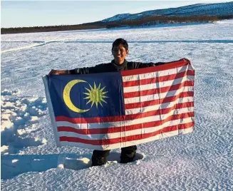  ?? — RIZAl KHALIF ?? Proudly holding up the Malaysian flag after completing the 300km journey across the Arctic, from Norway to Sweden, on a dog sleigh.