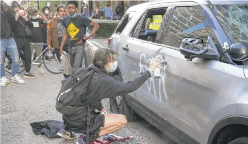  ?? ASHLEE REZIN GARCIA/SUN-TIMES ?? A protester sprays paint on a Chicago Police Department SUV on Kinzie Street near State Street on Saturday.